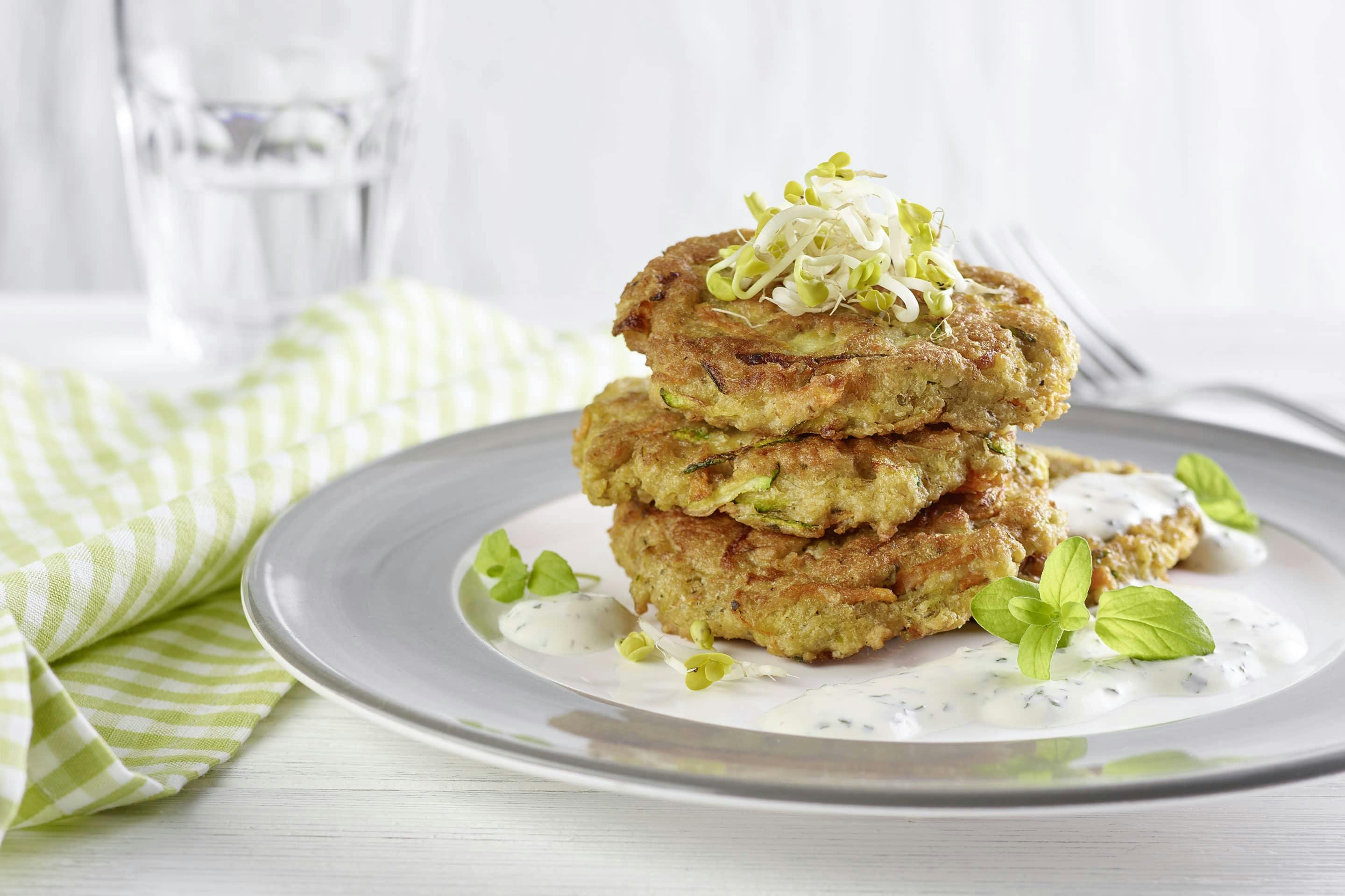 Carrot and zucchini patties with oatmeal and marjoram prepared on a plate with a gray rim and a green checkered napkin