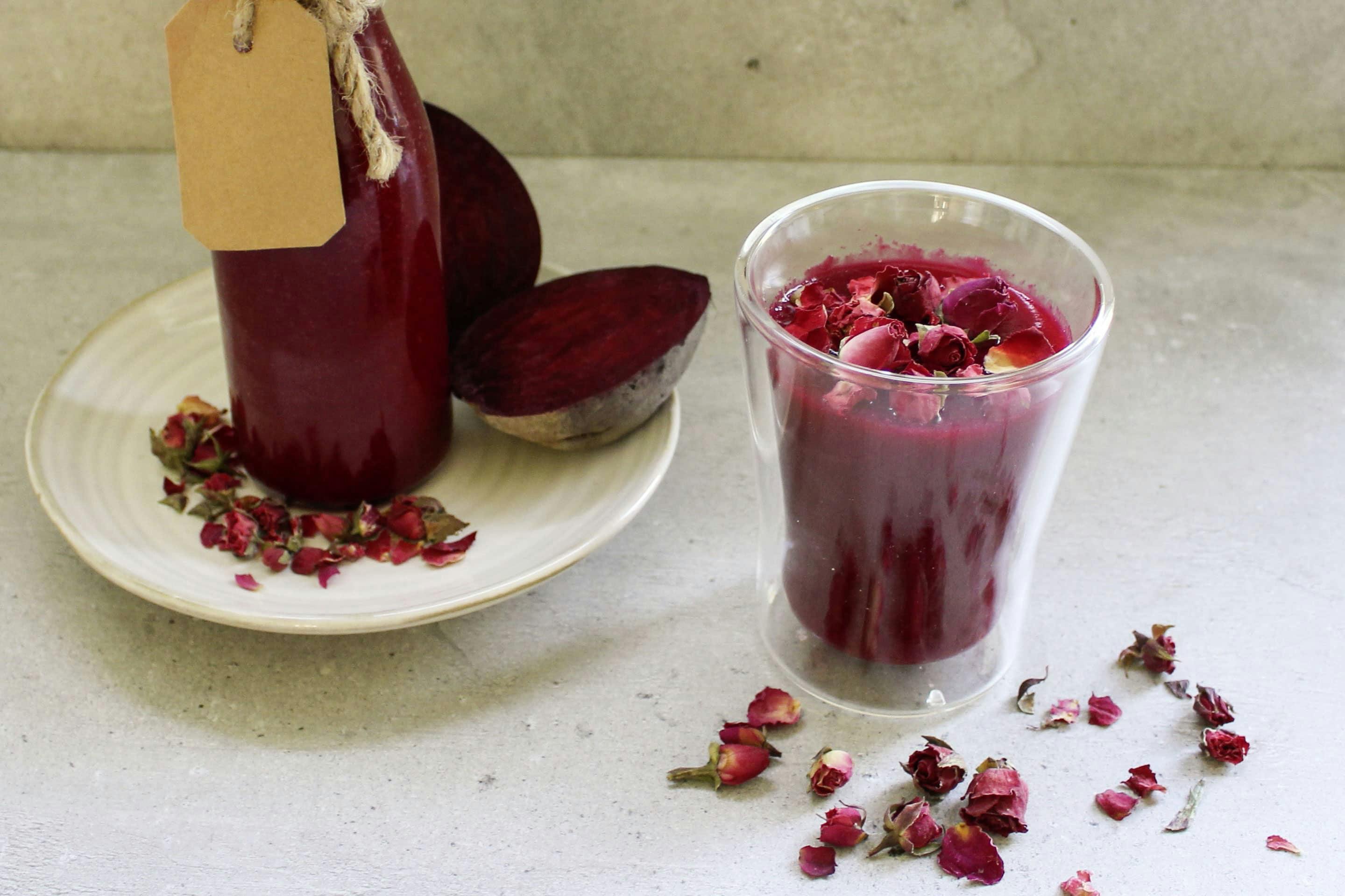 Beetroot smoothie with ground ginger in a glass garnished with rose petals