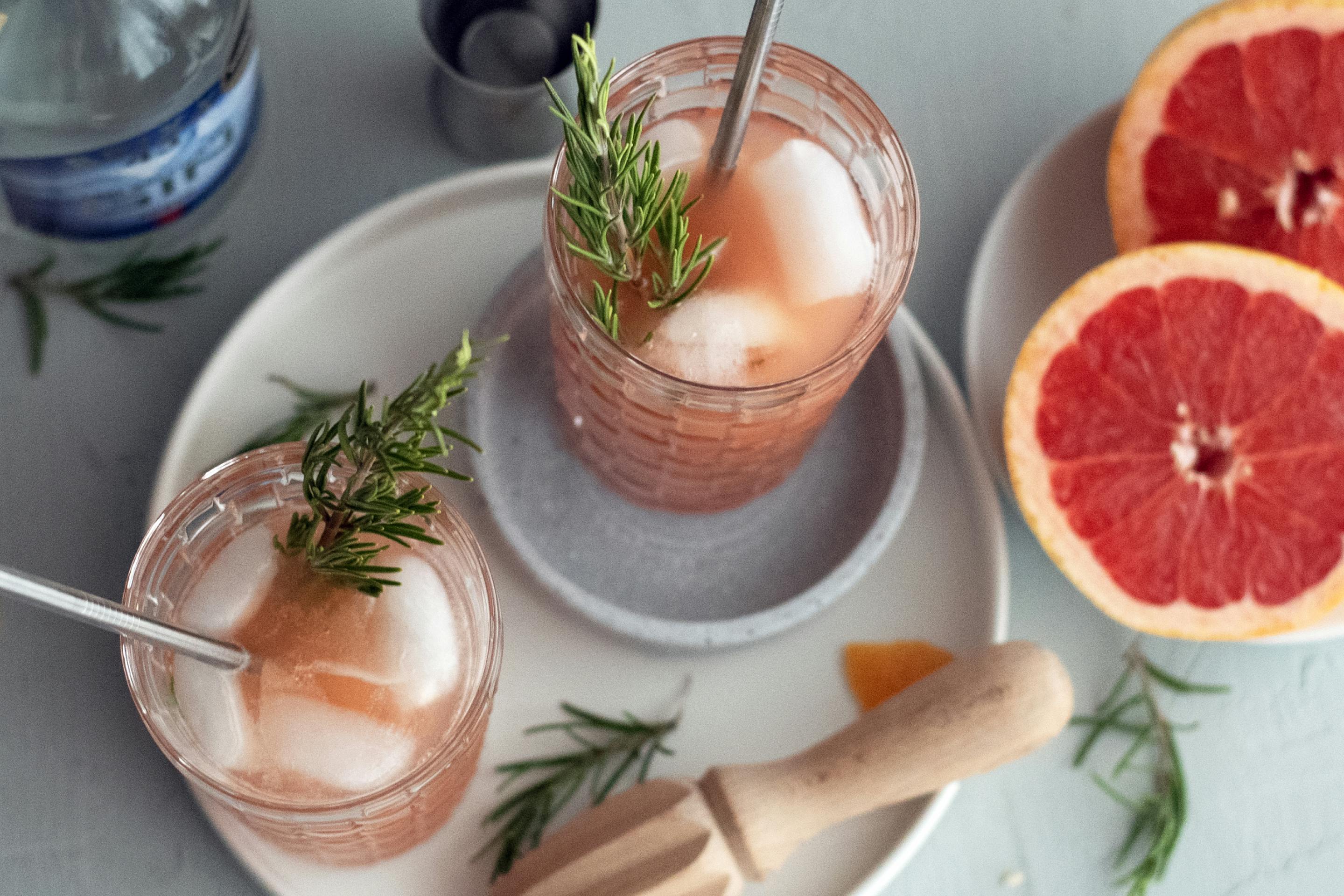Gin Getränk im Glas mit Rosmarinzweig, Grapefruit und Strohhalm