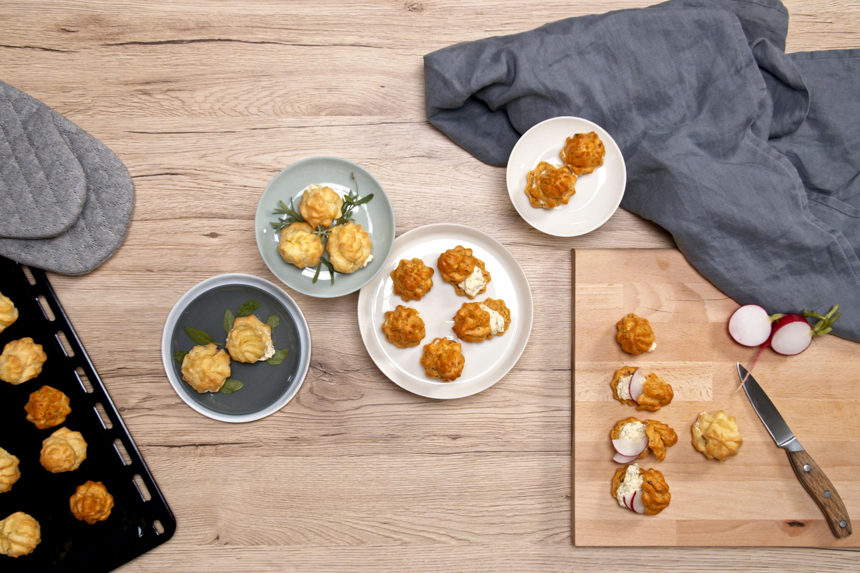 Hearty choux pastry donuts with cream cheese filling on different plates and a wooden board