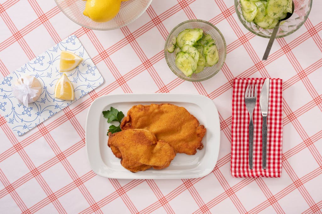 Two Wiener Schnitzel served with a cucumber salad garnished with dill.