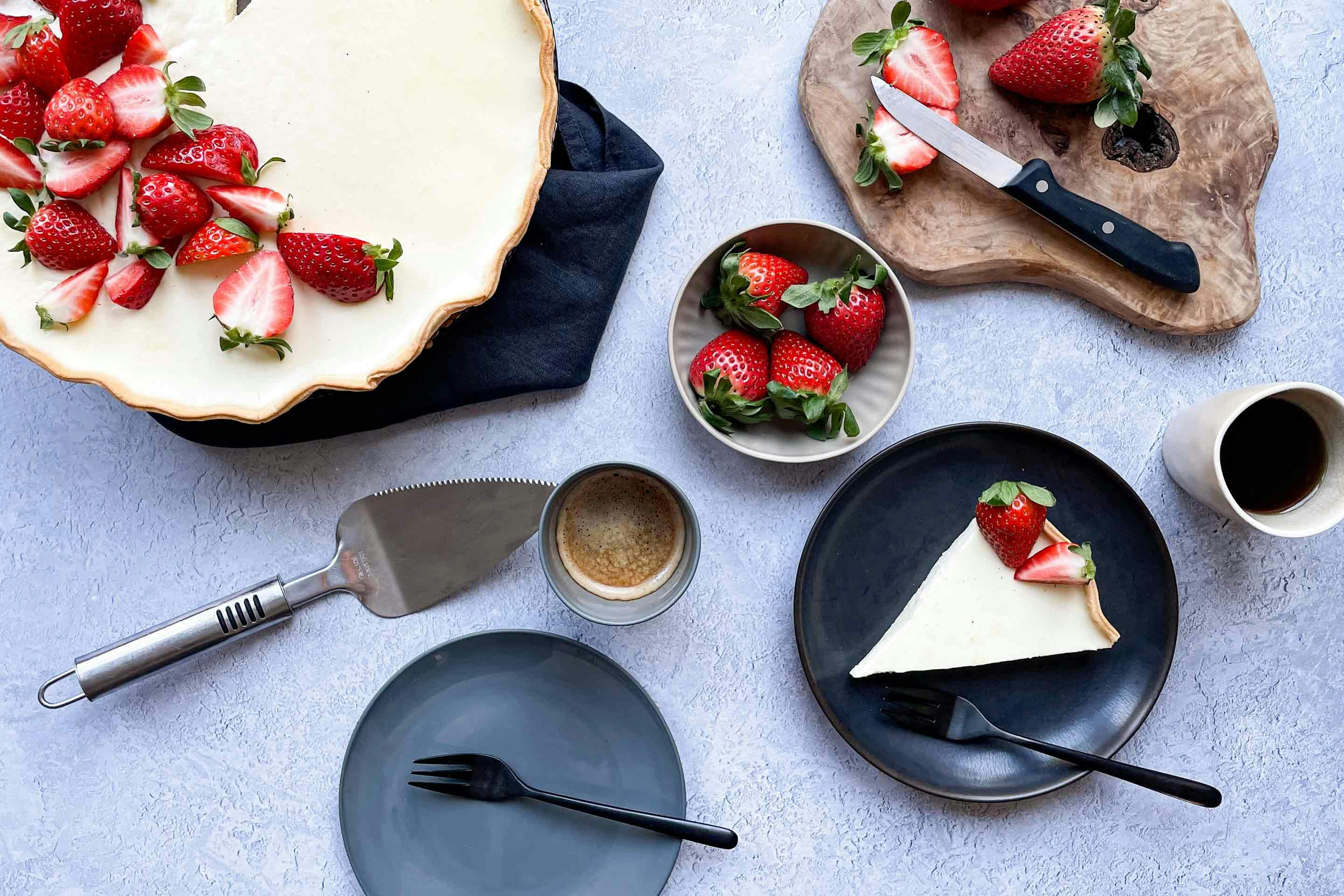Strawberry panna cotta tart served on a plate with a cup of coffee.
