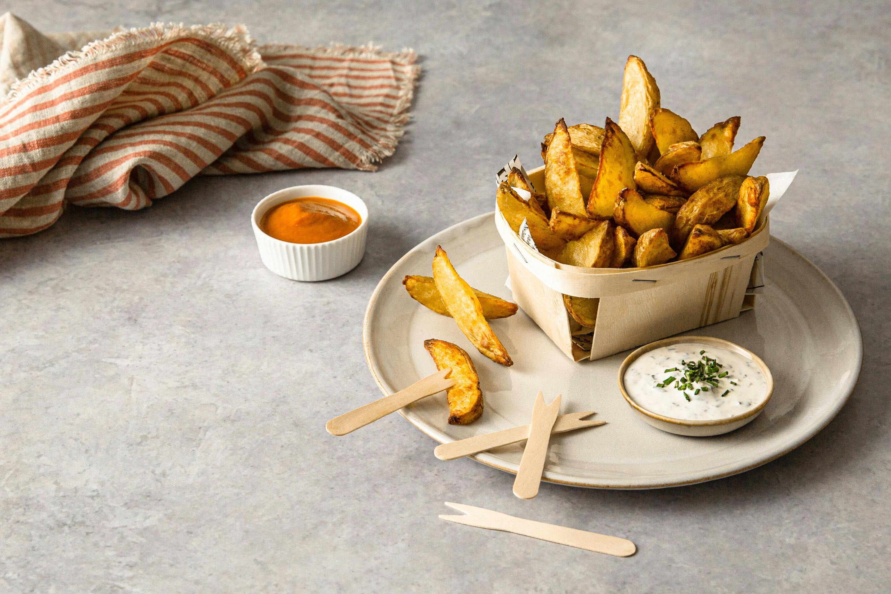 Crunchy Potato Wedges Served with Dips in a Wooden Basket on a Plate