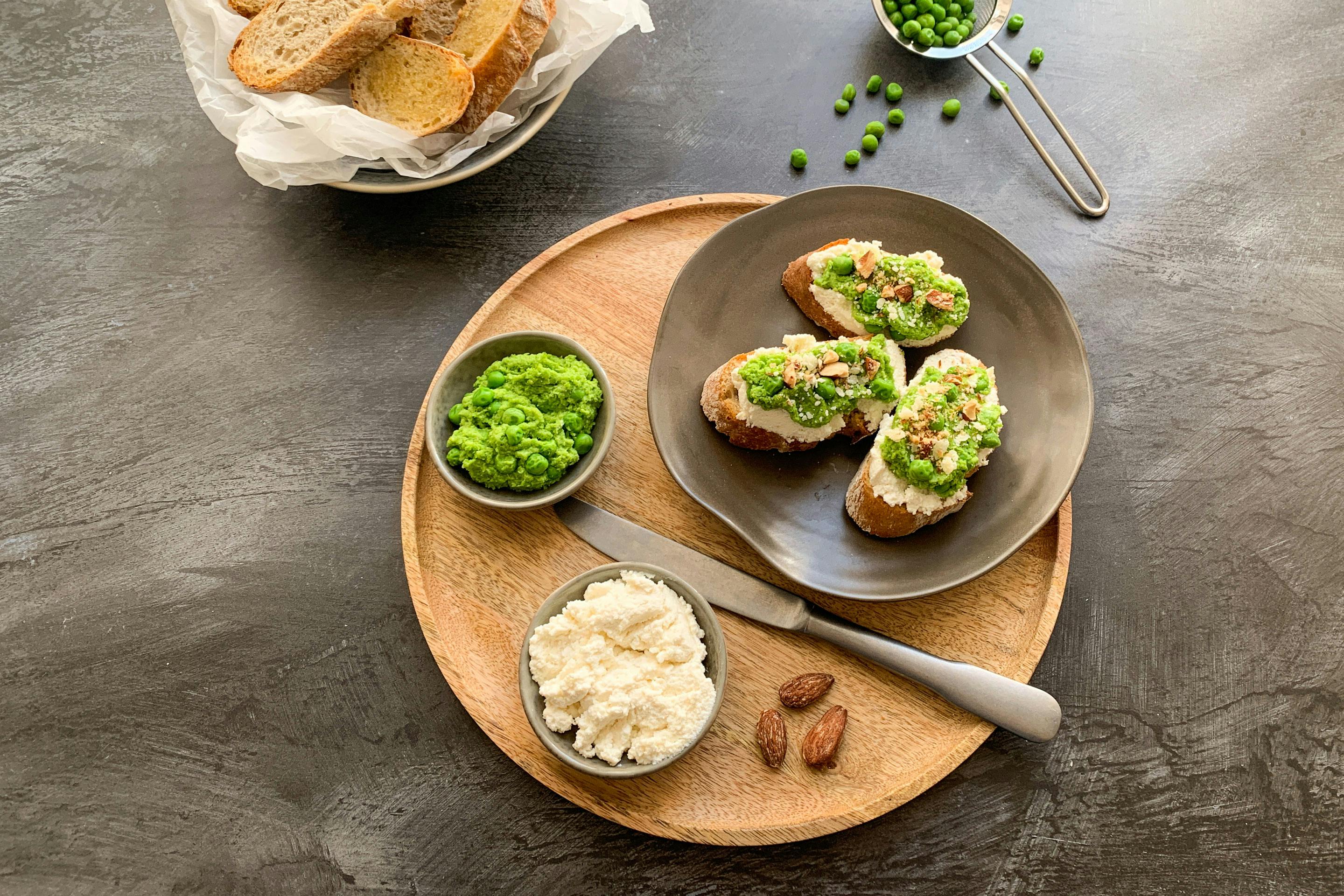 Pea and ricotta crostini served on a wooden plate
