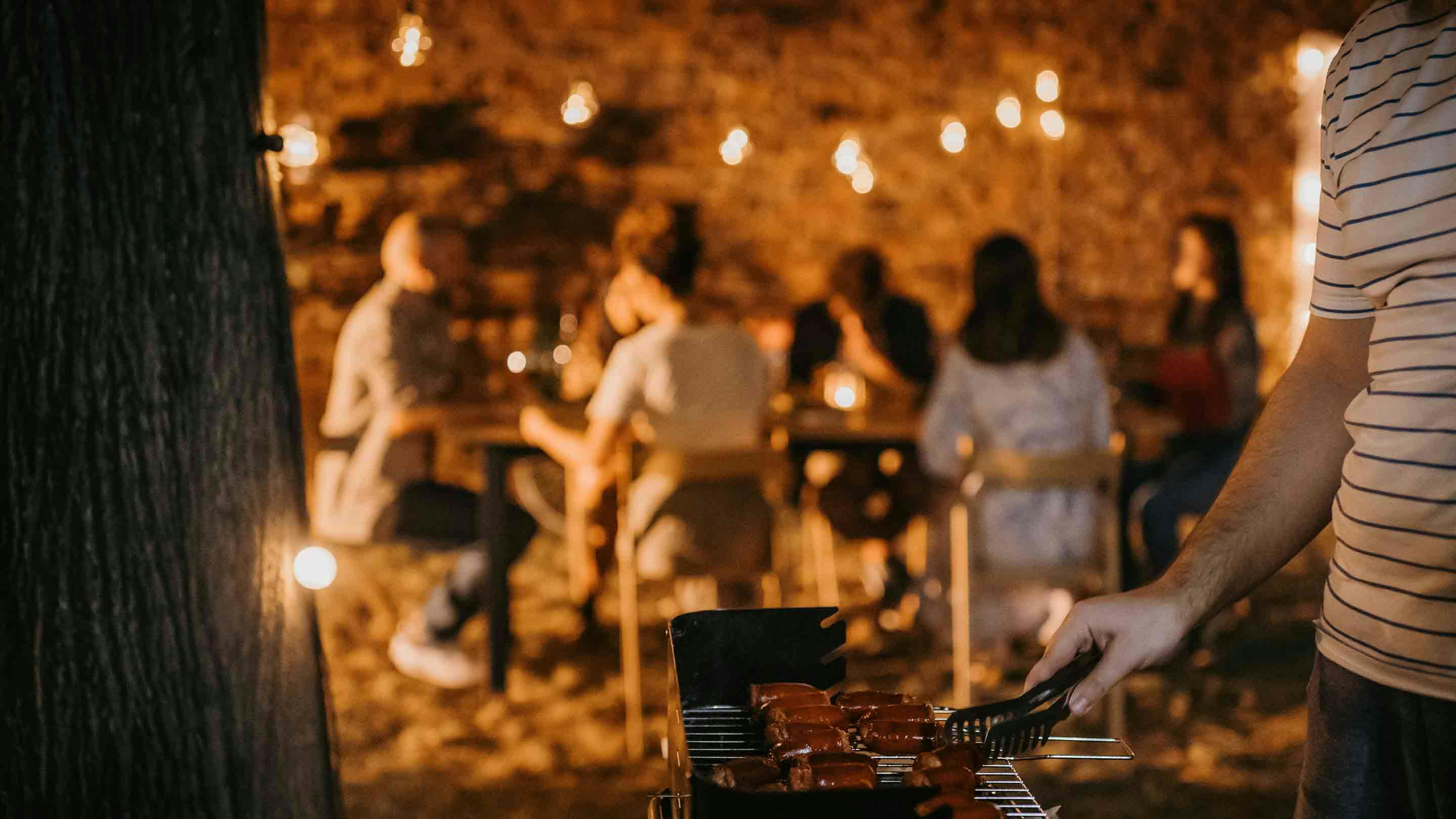 Friends enjoying a BBQ evening with fairy light decoration.