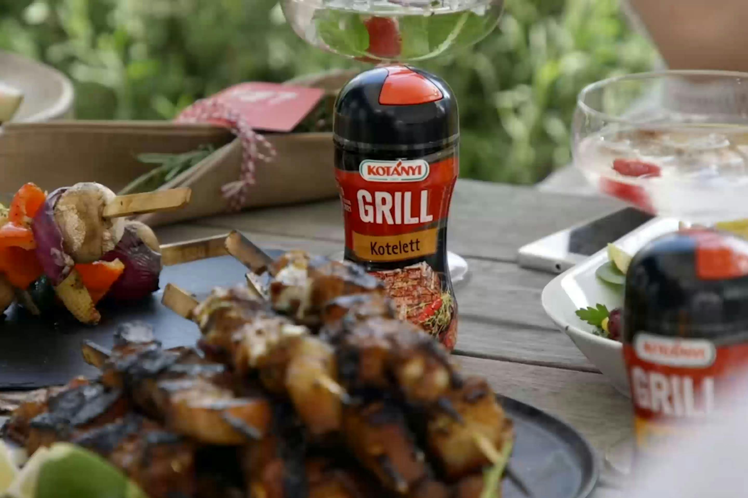 A Kotányi BBQ Shaker Can on a table with grilled food.