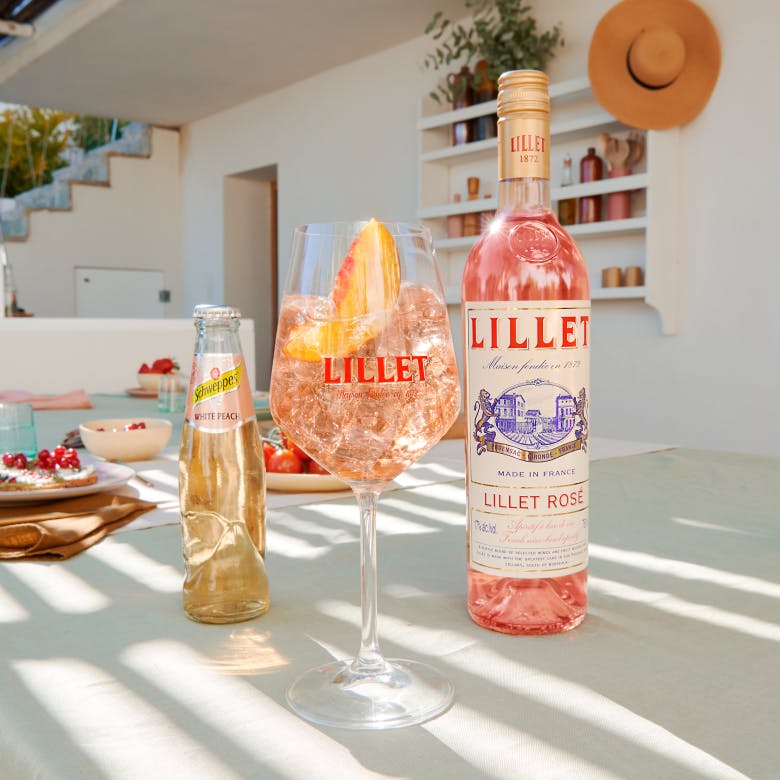 A glass of Lillet White Peach on a table outside.